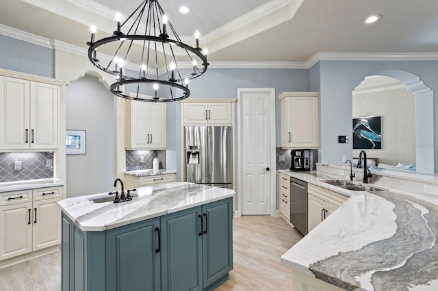 kitchen featuring light stone counters, sink, and an island with sink