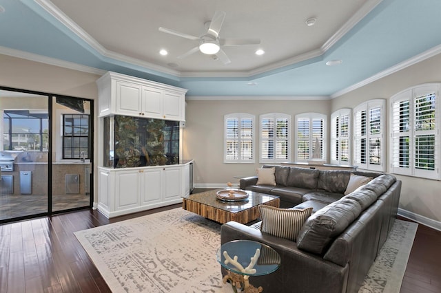 living room with crown molding, dark hardwood / wood-style floors, a raised ceiling, and ceiling fan