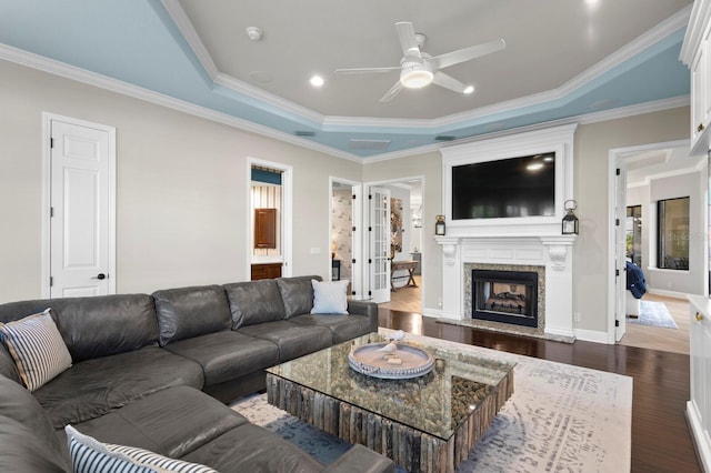 living room with ceiling fan, dark hardwood / wood-style floors, a fireplace, ornamental molding, and a raised ceiling