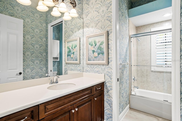 bathroom with vanity, bath / shower combo with glass door, wood-type flooring, and a notable chandelier