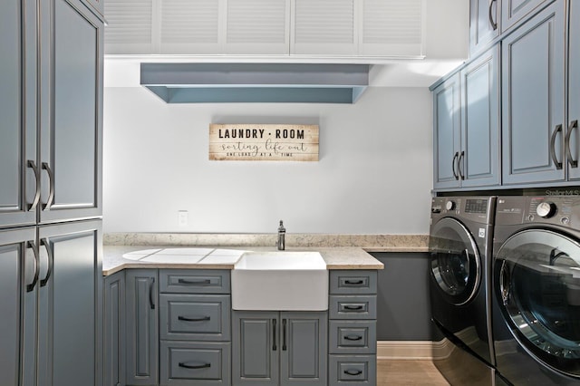 washroom featuring hardwood / wood-style flooring, cabinets, sink, and washing machine and clothes dryer