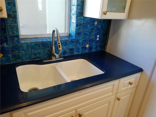 kitchen featuring backsplash, sink, and white cabinets