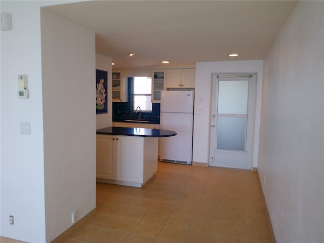 kitchen with white refrigerator, sink, and white cabinets