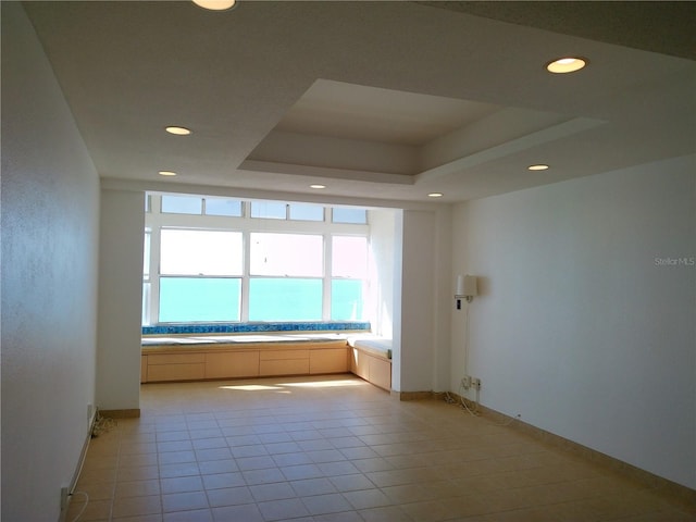 tiled spare room featuring a tray ceiling