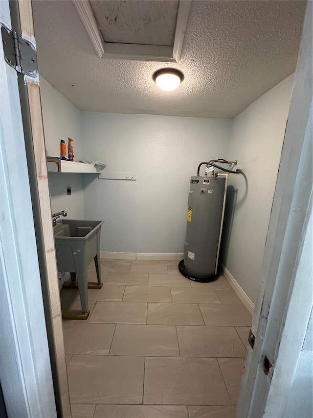 washroom with water heater, sink, and a textured ceiling