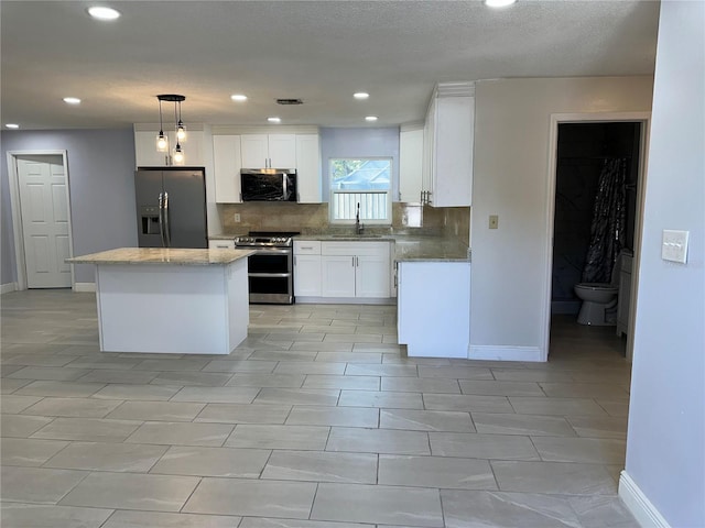 kitchen with sink, white cabinetry, decorative light fixtures, a center island, and appliances with stainless steel finishes