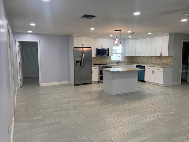 kitchen with stainless steel appliances, white cabinetry, hanging light fixtures, and a center island