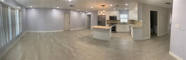 kitchen featuring a kitchen island, pendant lighting, white cabinetry, decorative backsplash, and stainless steel appliances