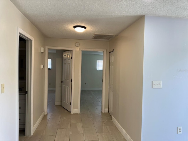 corridor featuring light tile patterned flooring and a textured ceiling