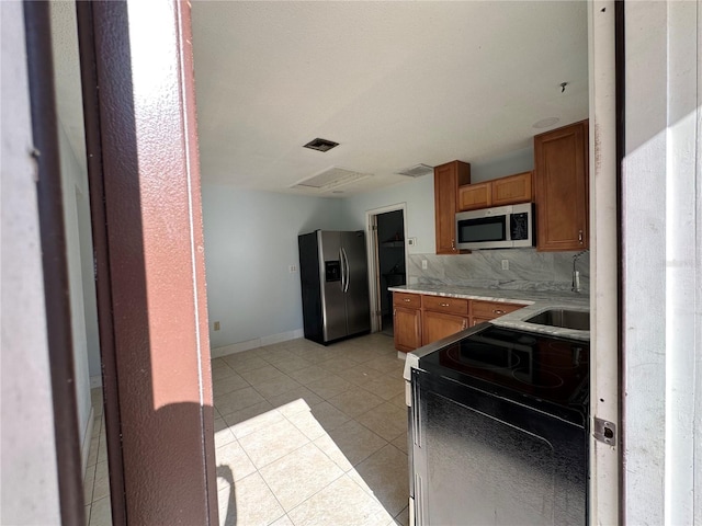 kitchen with appliances with stainless steel finishes, sink, decorative backsplash, and light tile patterned floors