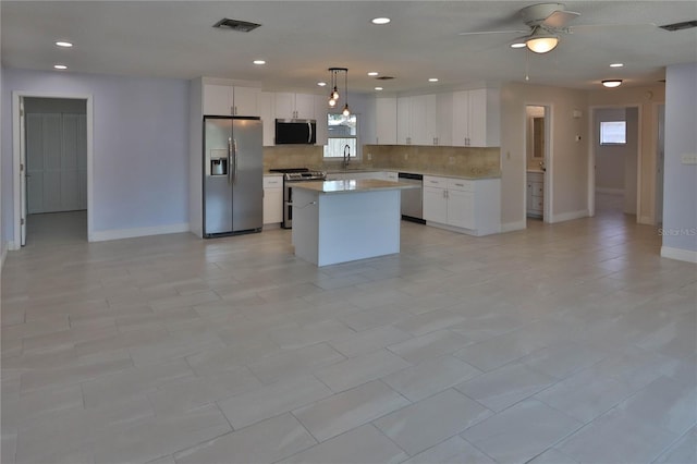 5729 13th St, Zephyrhills, FL 33542 - kitchen featuring stainless steel appliances, tasteful backsplash, baseboards, a center island, and light countertops