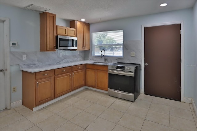 5729 13th St, Zephyrhills, FL 33542 - kitchen featuring stainless steel appliances, a sink, brown cabinetry, recessed lighting, and light stone countertops