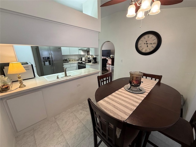 tiled dining room featuring sink, ceiling fan, and a high ceiling