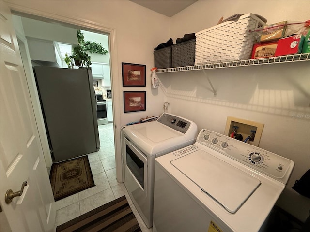 laundry area with light tile patterned floors and washer and clothes dryer