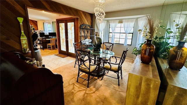 tiled dining area with french doors, a textured ceiling, and wood walls