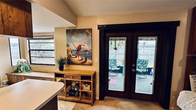 doorway to outside with light carpet, french doors, and a textured ceiling