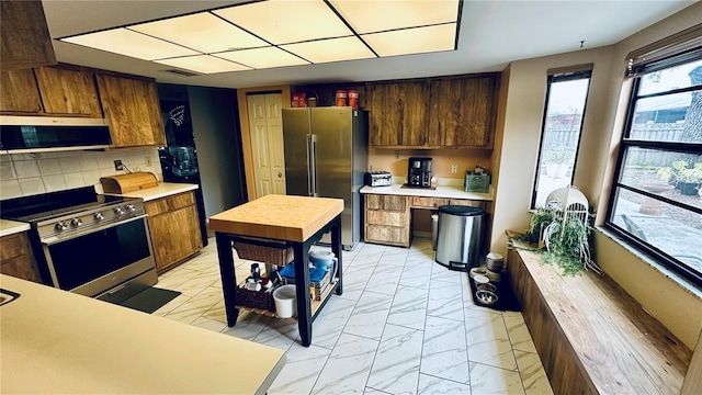 kitchen featuring tasteful backsplash, appliances with stainless steel finishes, and built in desk