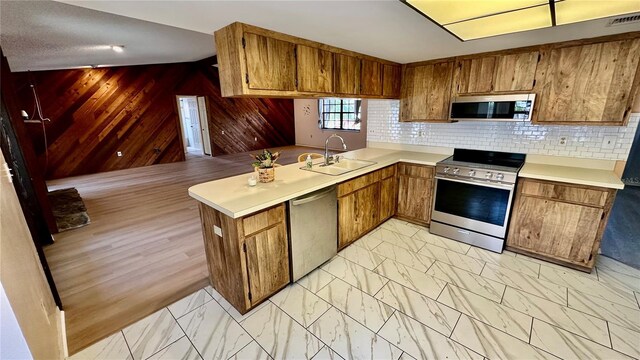 1670 Monterey Dr, Clearwater, FL 33756 - kitchen with stainless steel appliances, a sink, brown cabinetry, light countertops, and light marble finish floors