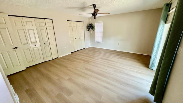 1670 Monterey Dr, Clearwater, FL 33756 - unfurnished bedroom featuring multiple closets, a textured ceiling, wood finished floors, and baseboards