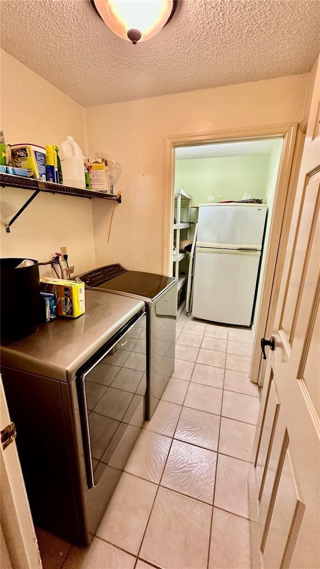 1670 Monterey Dr, Clearwater, FL 33756 - laundry room featuring washer and clothes dryer, a textured ceiling, and light tile patterned flooring