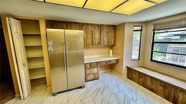 1670 Monterey Dr, Clearwater, FL 33756 - kitchen with freestanding refrigerator, light marble finish flooring, brown cabinetry, light countertops, and baseboards