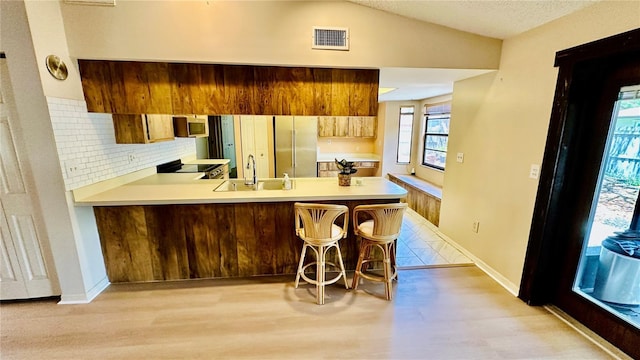 1670 Monterey Dr, Clearwater, FL 33756 - kitchen with stainless steel appliances, a sink, light wood-type flooring, a peninsula, and light countertops