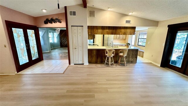 1670 Monterey Dr, Clearwater, FL 33756 - kitchen featuring light countertops, light wood-style floors, french doors, a kitchen breakfast bar, and baseboards