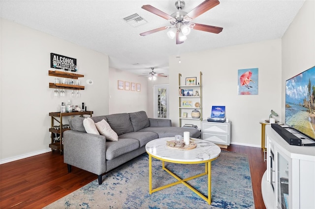 living room with ceiling fan, dark wood-type flooring, and a textured ceiling