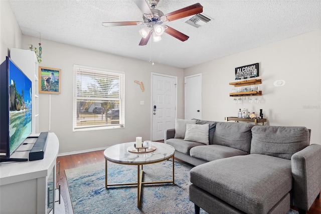 living room with ceiling fan, hardwood / wood-style floors, and a textured ceiling