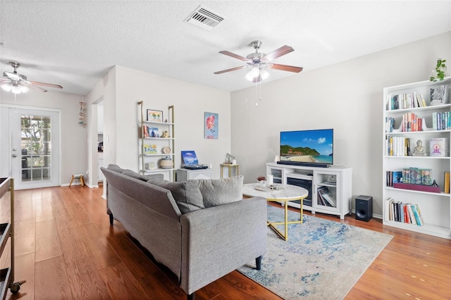 living room featuring ceiling fan, hardwood / wood-style floors, and a textured ceiling