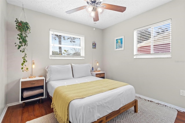 bedroom featuring dark wood-type flooring, ceiling fan, multiple windows, and a textured ceiling