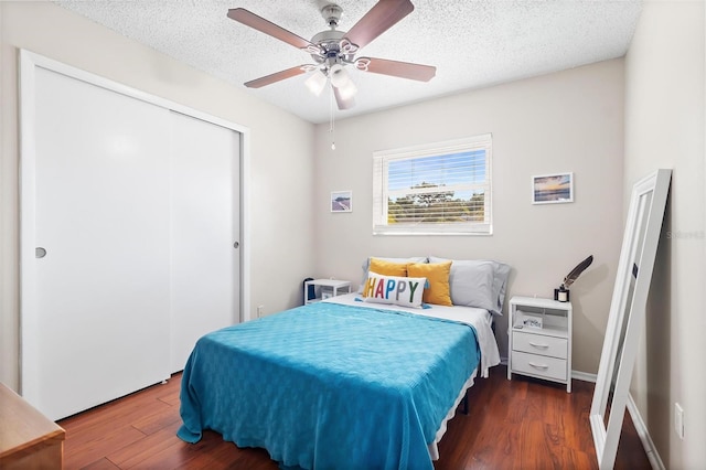 bedroom with ceiling fan, a closet, dark hardwood / wood-style floors, and a textured ceiling