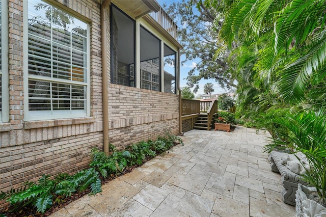 view of side of property featuring a wooden deck and a patio area