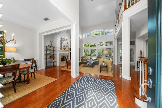 foyer featuring a high ceiling, a chandelier, hardwood / wood-style floors, and a fireplace