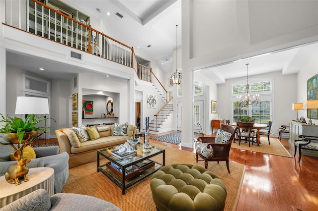 living room featuring hardwood / wood-style flooring, a towering ceiling, and a notable chandelier