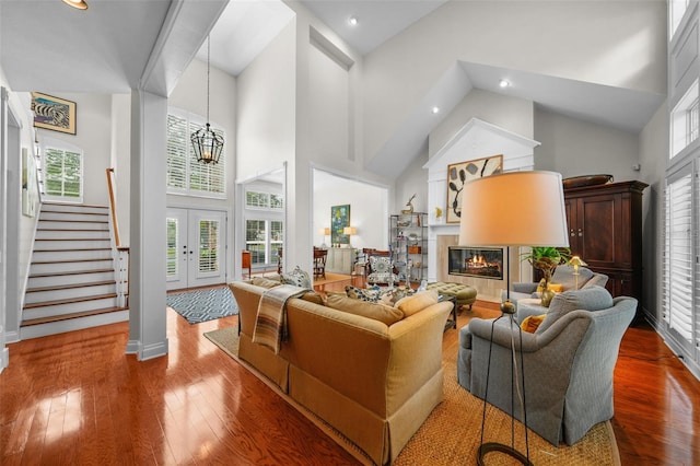 living room featuring wood-type flooring, a chandelier, and high vaulted ceiling