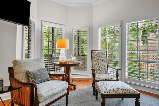 living area featuring a healthy amount of sunlight, ornamental molding, and hardwood / wood-style floors