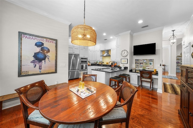 dining room featuring sink, dark wood-type flooring, and ornamental molding