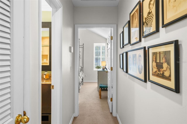 hallway featuring light colored carpet and lofted ceiling