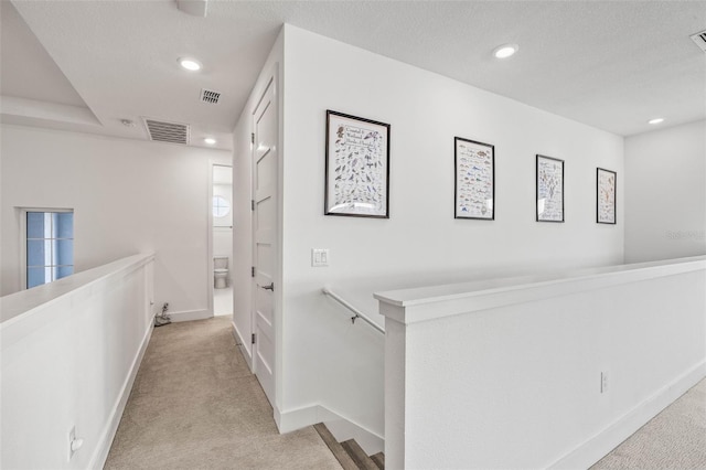 hallway featuring light carpet and a textured ceiling