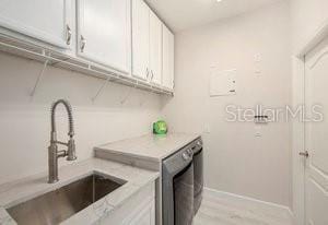 laundry room with independent washer and dryer, cabinets, light hardwood / wood-style floors, and sink