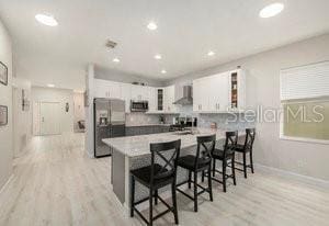 kitchen with white cabinetry, stainless steel appliances, a kitchen breakfast bar, and kitchen peninsula