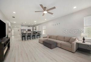 living room with ceiling fan and light wood-type flooring