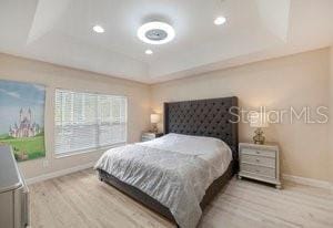 bedroom featuring light hardwood / wood-style floors and a tray ceiling