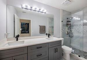 bathroom featuring vanity, a shower with door, and toilet