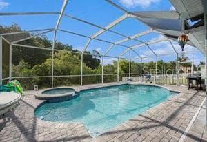 view of swimming pool with a patio area, an in ground hot tub, and glass enclosure