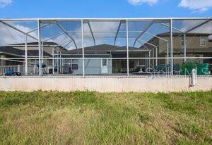 back of house with glass enclosure and a lawn