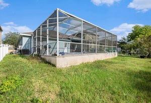 rear view of house featuring glass enclosure and a lawn