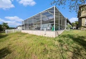 rear view of house featuring a yard and glass enclosure