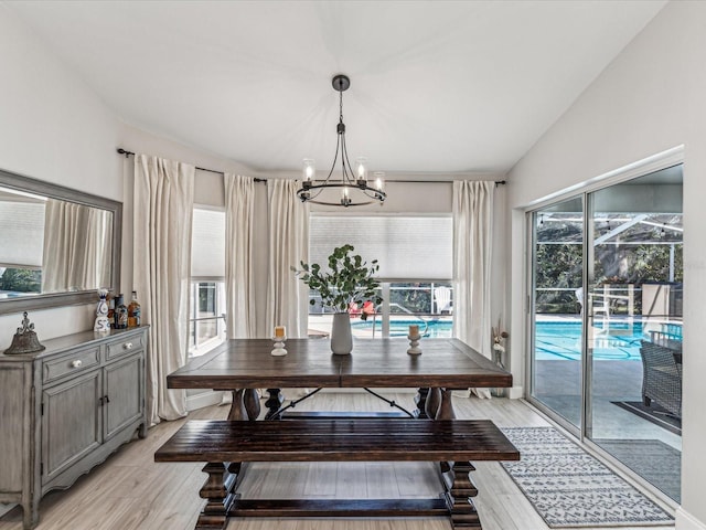 dining room with lofted ceiling, light wood finished floors, and a notable chandelier